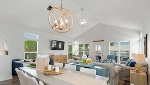 A spacious living area with a dining table, seating, a chandelier, and a television. - Casa Mimosa: Your Private Beach Escape with Pool, Bikes & Steps to the Sand (Santa Rosa Beach)