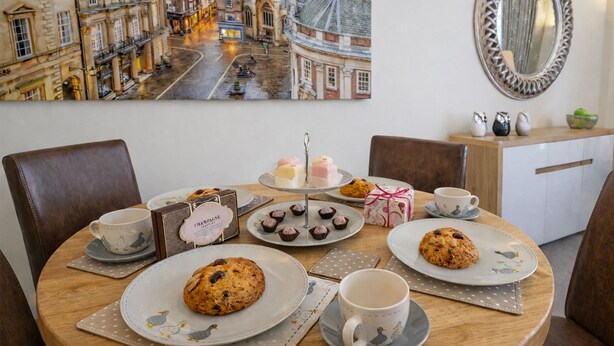 Une table à manger avec des assiettes de biscuits, une théière et une tasse à thé.