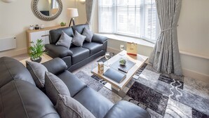 Un salon moderne avec un canapé en cuir noir, une table basse et une plante en pot.