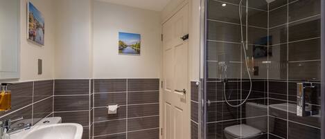 Un baño moderno con ducha de vidrio, lavamanos blanco y un inodoro.