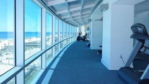 A corridor with large windows, a treadmill, and exercise equipment. - Serenity: Island Tower 702 3BR 3BA, 2 Gulf-Front Masters, + Free Beach Service!! (Gulf Shores)