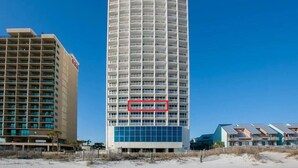 A tall, cylindrical hotel with multiple balconies and a blue facade. - Serenity: Island Tower 702 3BR 3BA, 2 Gulf-Front Masters, + Free Beach Service!! (Gulf Shores)
