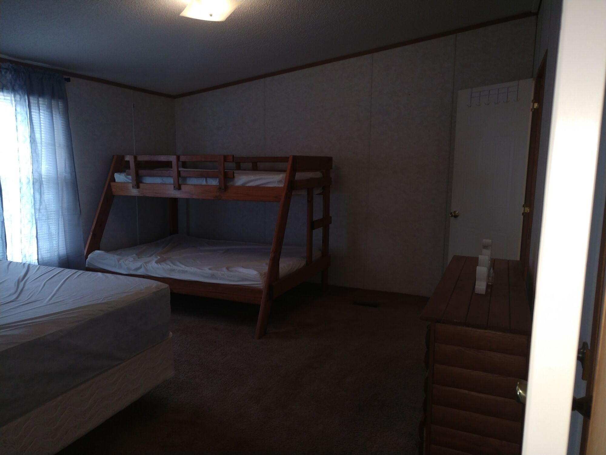 A room with bunk beds, a desk, and a door.