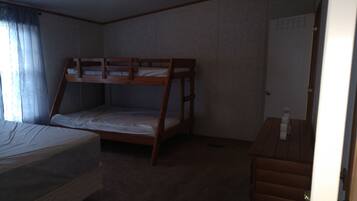 A room with bunk beds, a desk, and a door.
