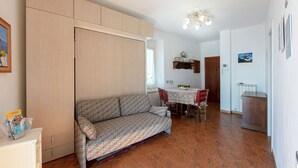A compact living space with a sofa, a dining table, and a kitchenette area.