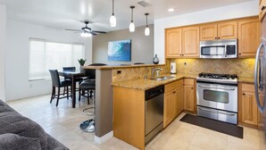 Una cocina compacta con armarios de madera, microondas integrado, estufa y lavavajillas.