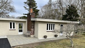 A single-story house with a brick chimney, a front porch with a bench, and a small tree in the yard. - South Chatham cottage walk to beaches, dining, tennis, shops, bike path.  (Chatham)