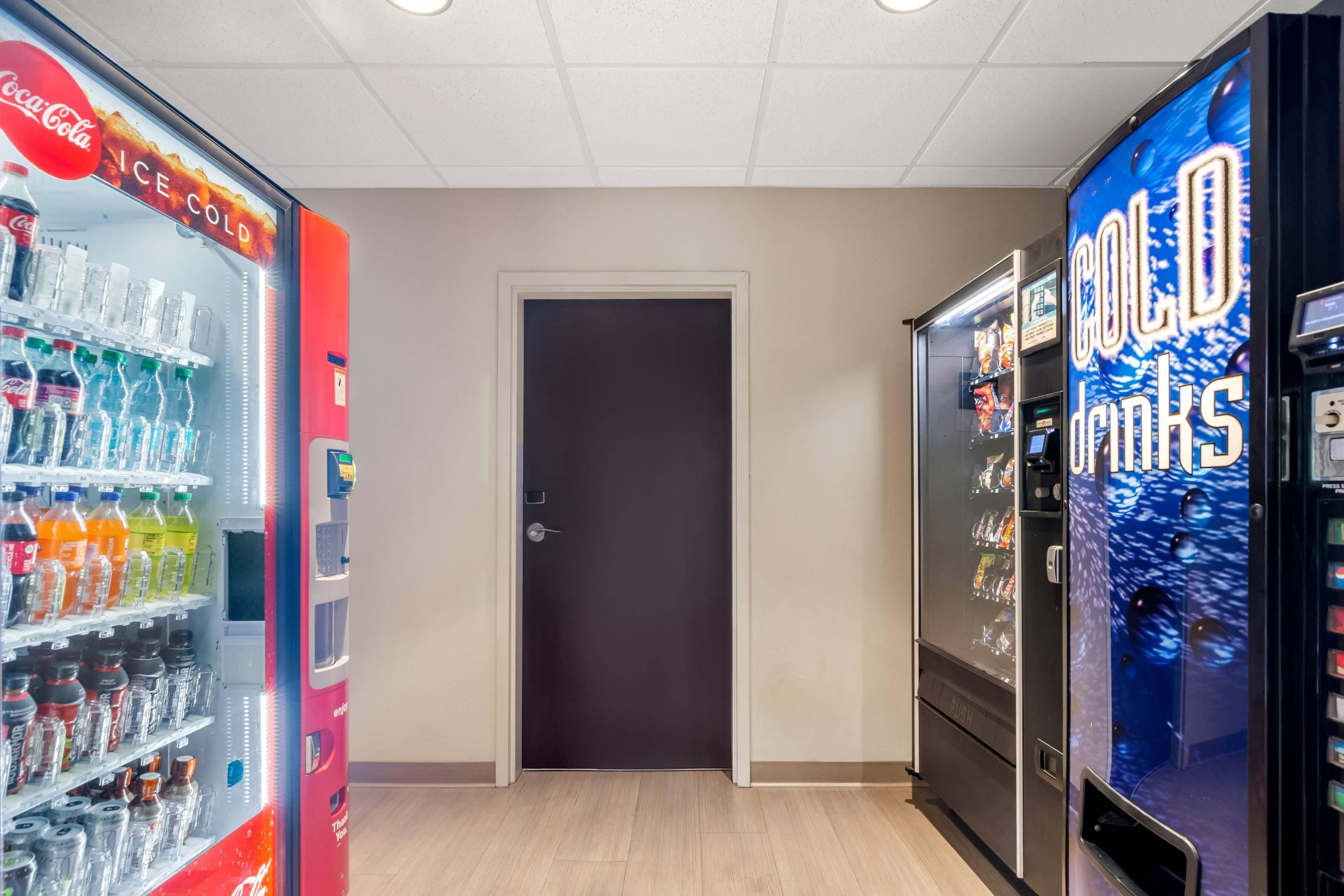 Un'area con distributori automatici di Coca-Cola e bevande fredde, una porta e un pavimento in legno.