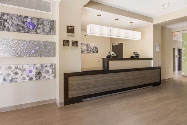 A reception desk with a modern design, a large mirror above it, and wall art depicting flowers and leaves.