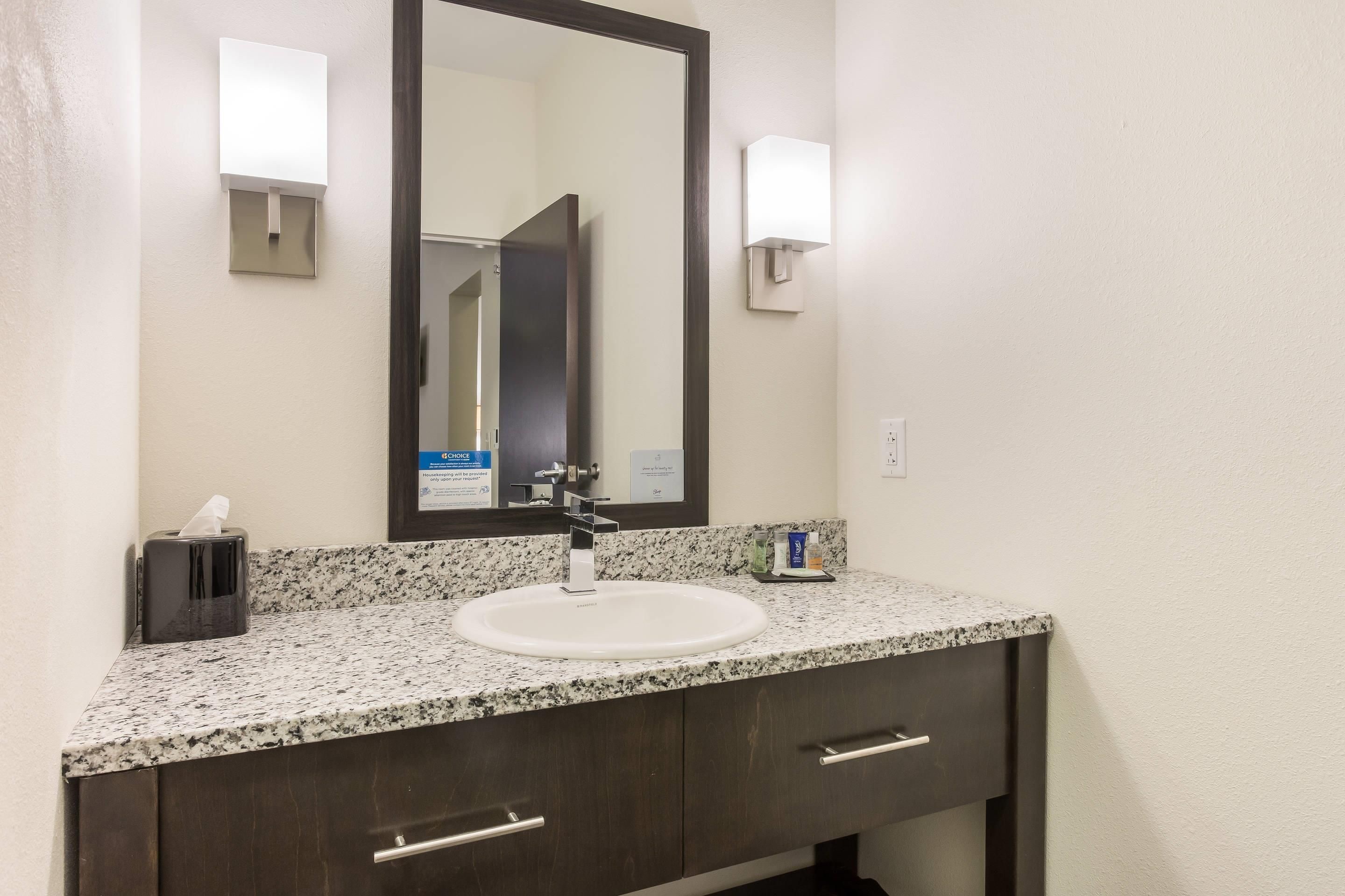 A bathroom with a white sink, dark wooden vanity, and a large mirror.