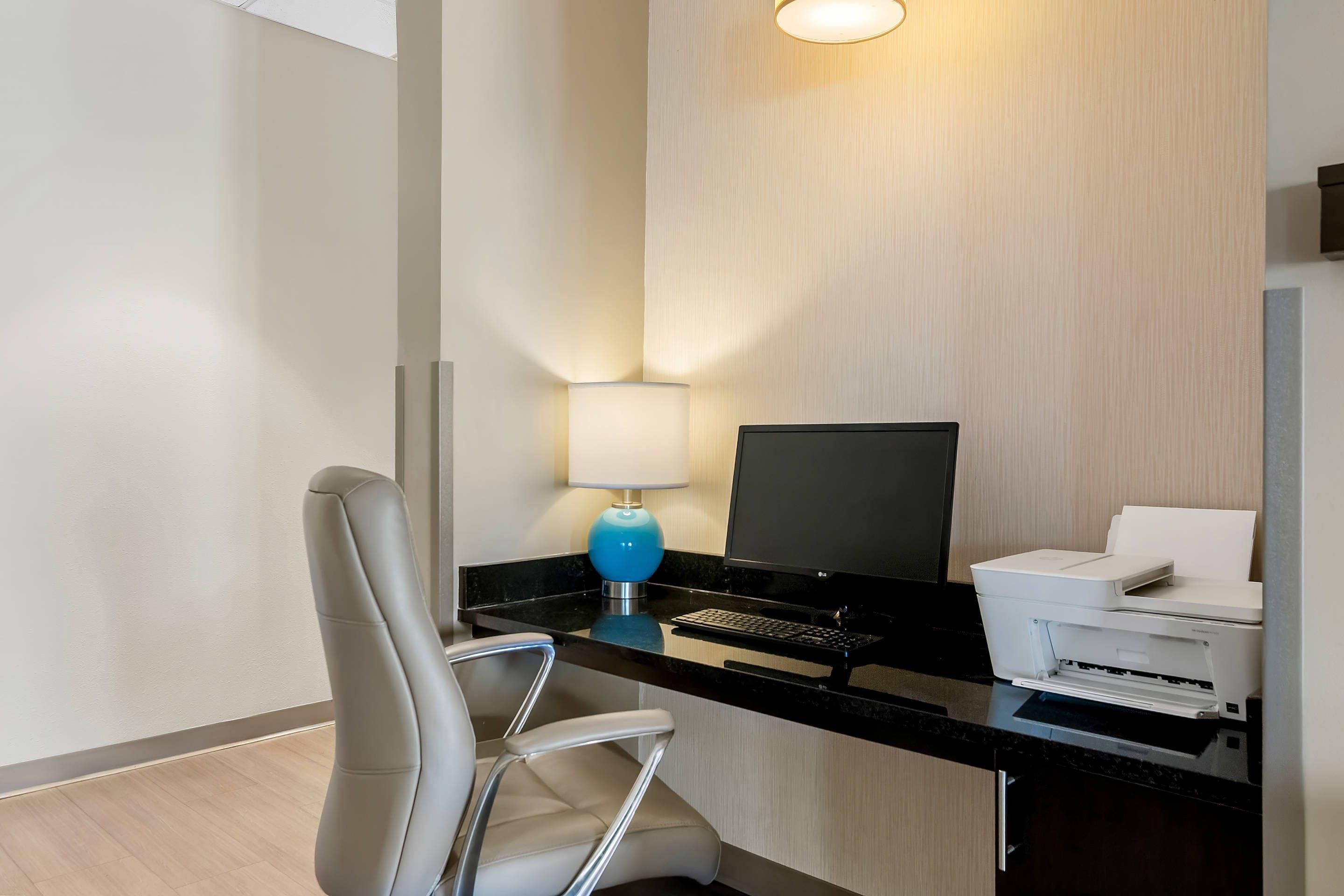 Une chambre d’hôtel équipée d’un bureau, d’un ordinateur, d’une imprimante, d’une chaise et d’une lampe.