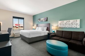 A hotel room with a bed, a desk, a chair, a couch, and a window with a view of a building. - Sleep Inn & Suites Webb City (Webb City)