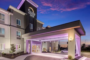A Sleep Inn hotel with a modern design, featuring a covered entrance and a well-lit facade.