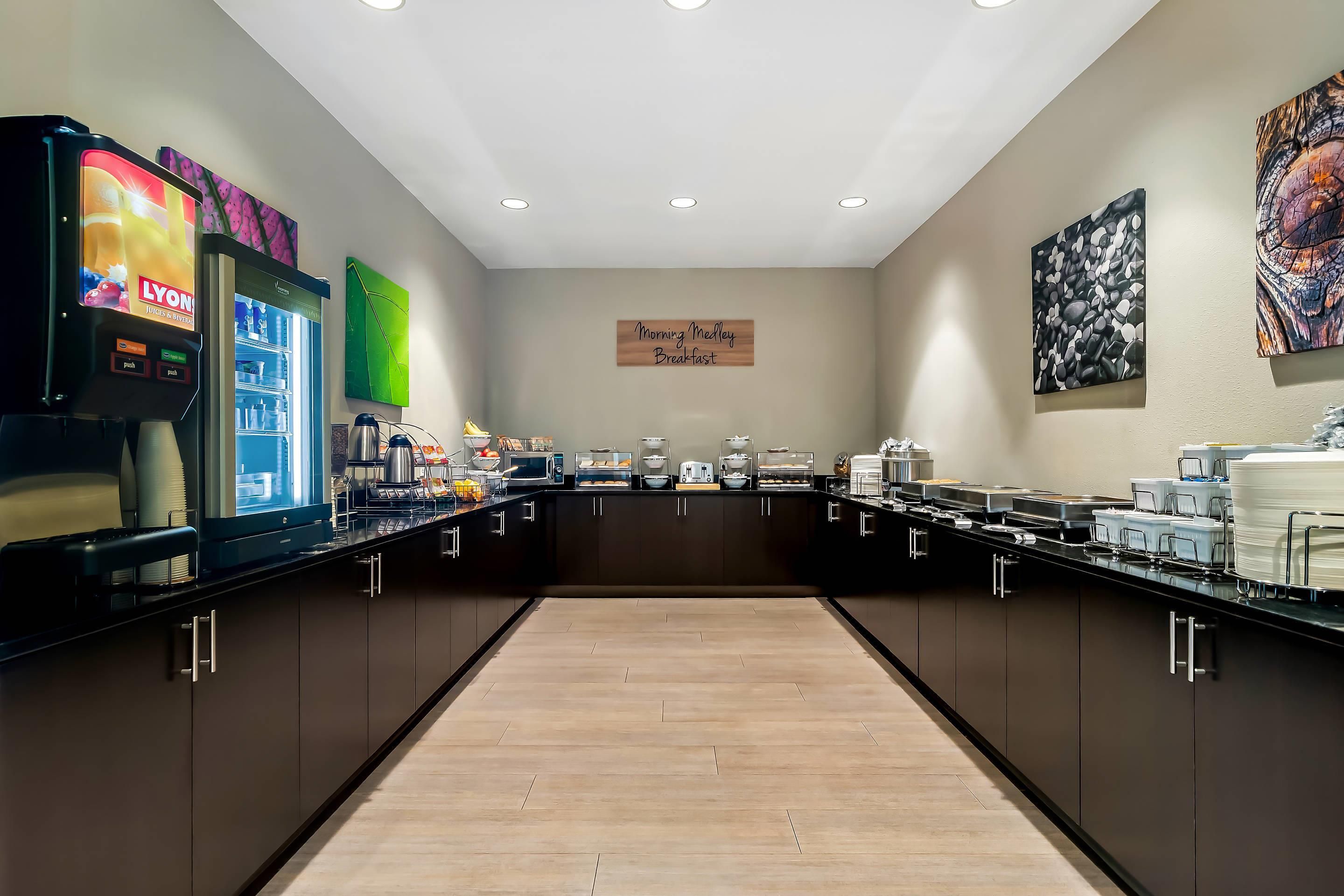 A breakfast buffet area with a variety of food options, a refrigerator, and a coffee station.