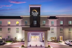 A Sleep Inn hotel with a modern facade, multiple windows, and a well-lit entrance.