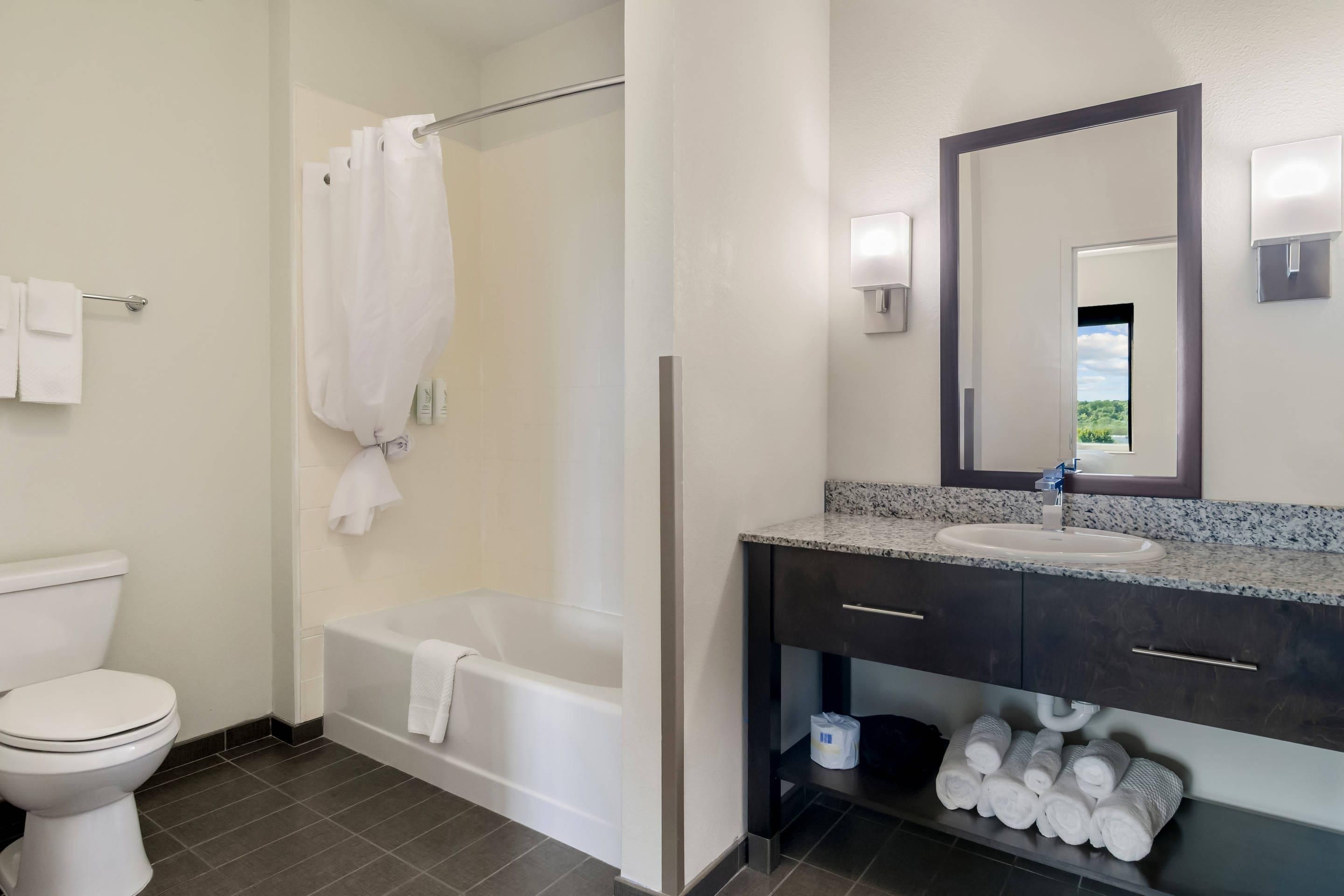 A bathroom with a toilet, bathtub, and a sink with a mirror.