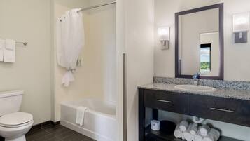 A bathroom with a toilet, bathtub, and a sink with a mirror.