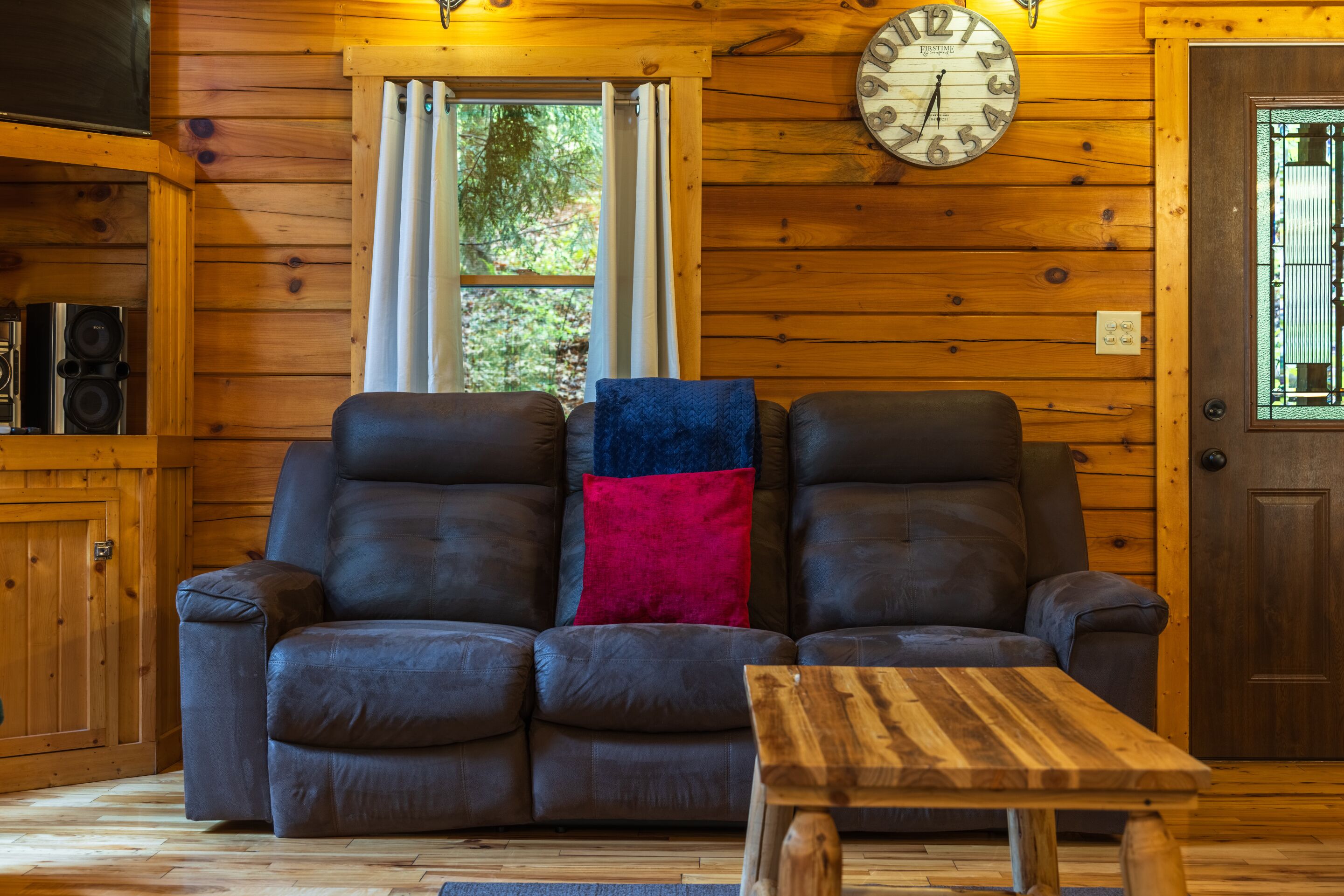 Ein Holzinnenraum mit einem Ledersofa, einem Holztisch und einer Wanduhr.