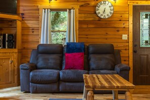 A wooden interior with a leather sofa, a wooden coffee table, and a wall clock.