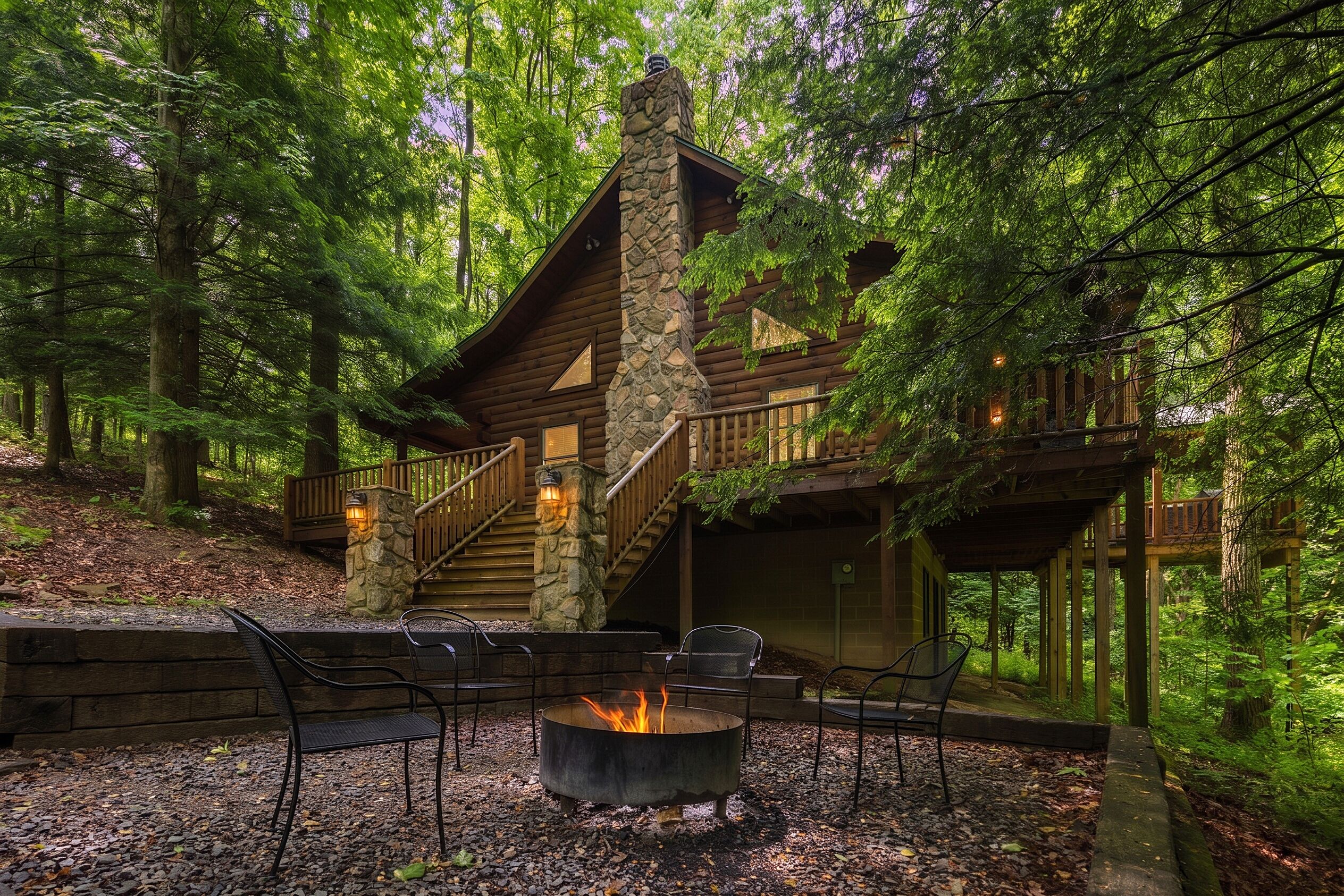 Eine Holzhütte mit Steinofen, einer Holzterrasse und einem Feuerkorb, der von Stühlen umgeben ist.