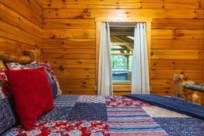 A wooden cabin interior with a bed, curtains, and a window. - Leaning Tree - Cozy Log Cabin in the Hocking Hills (Logan)