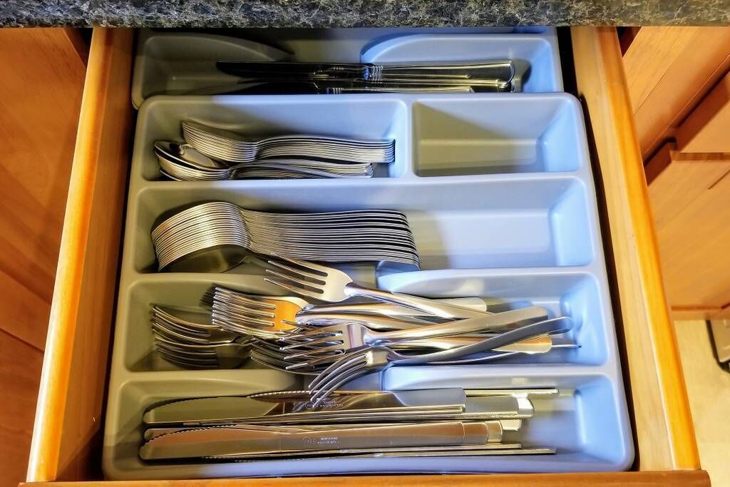 A drawer with compartments containing various kitchen utensils.