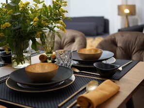 A dining table set with bowls, plates, and cutlery, accompanied by a vase of yellow flowers and a candle. - Duplex Apartment Granada City Centre (Granada)