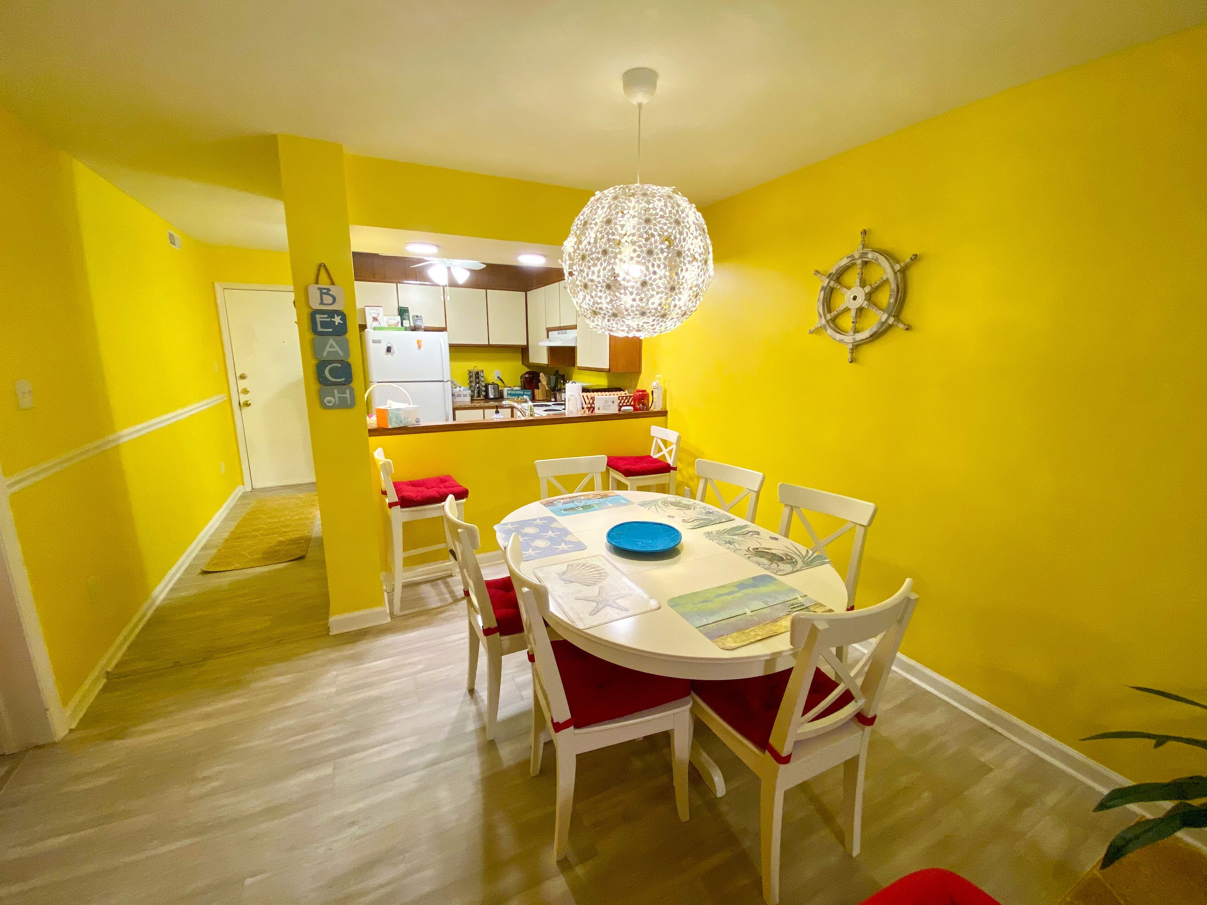 A dining area with a round table, white chairs, and a chandelier.