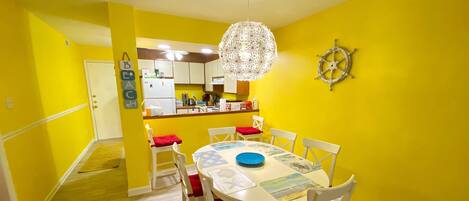 A dining area with a round table, white chairs, and a chandelier.