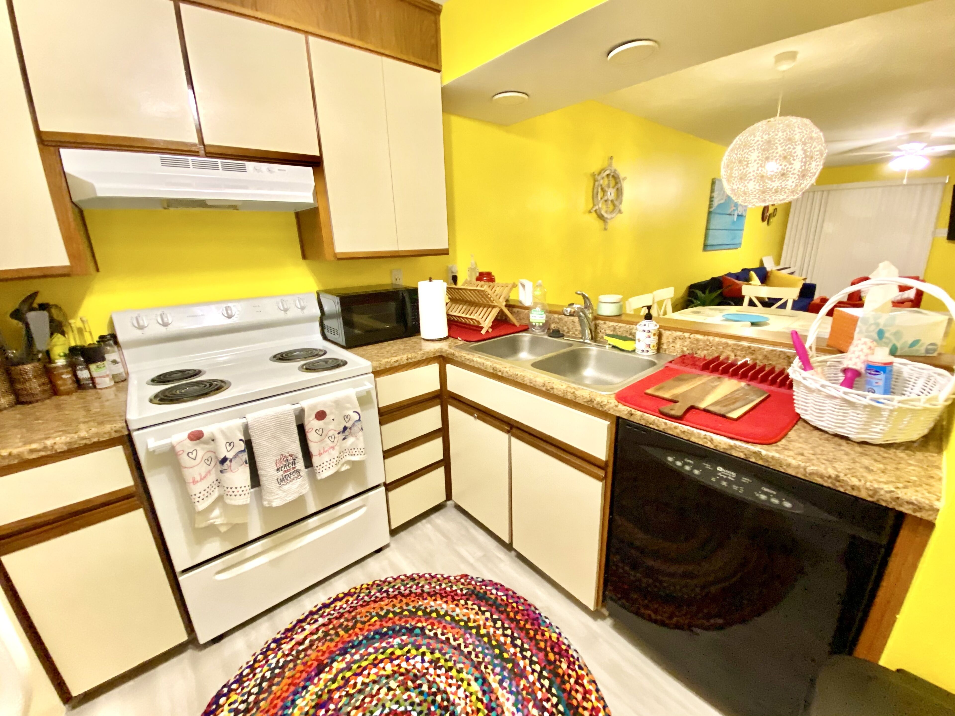 A compact kitchen with a stove, microwave, sink, and dishwasher.