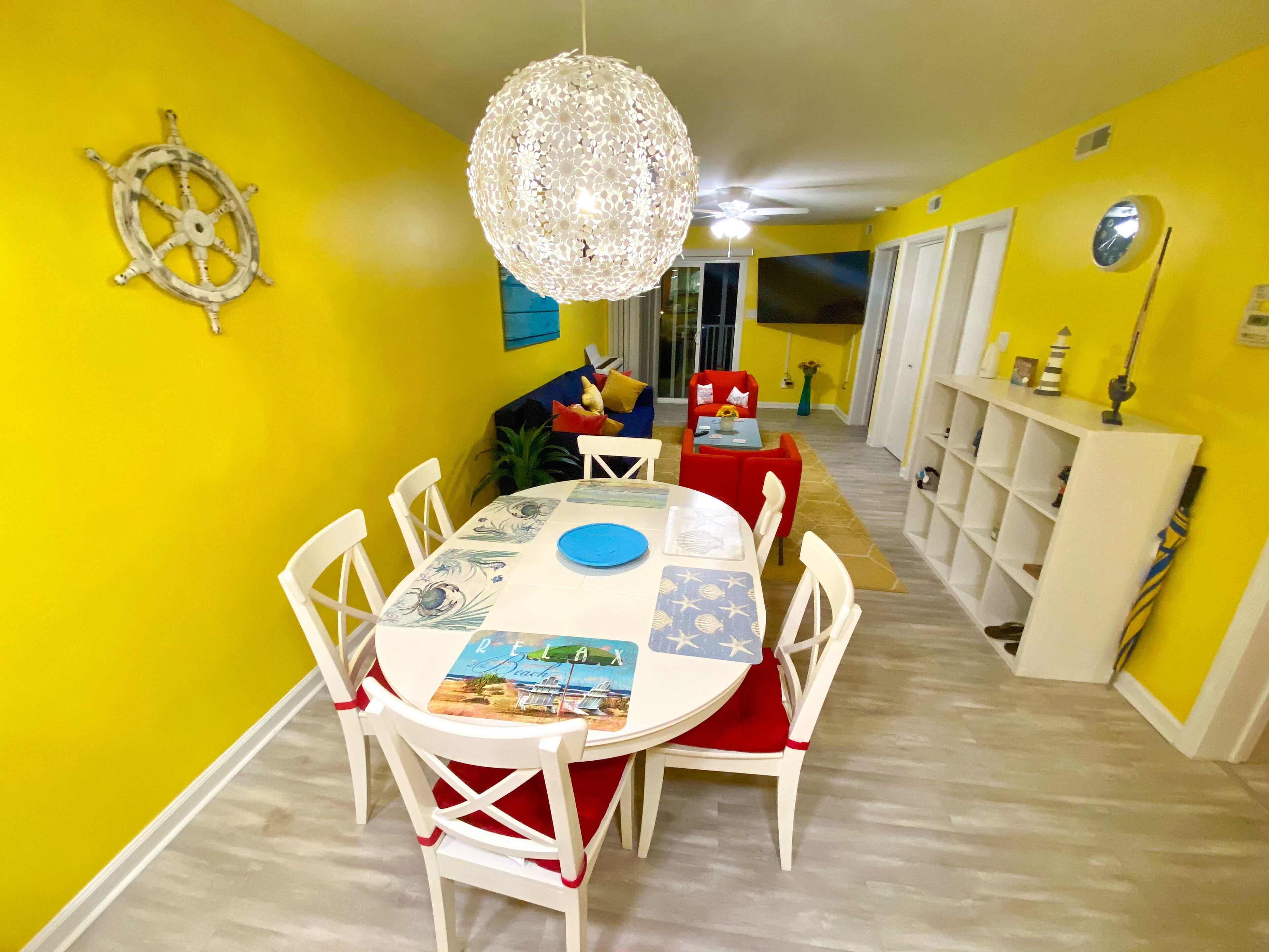 A dining area with a round table, white chairs, and a decorative ceiling light.