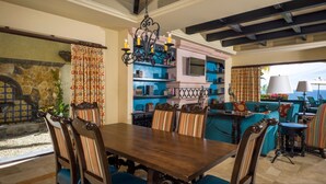 A dining area with a wooden table and chairs, a chandelier, and a view of the sea. - <br>CHRISTMAS & NEW YEARS EVE  4 BEDROOM LUXURY RESIDENCE AT QUIVIRA LOS CABOS (Cabo San lucas)