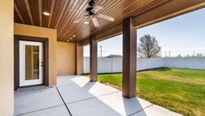 A covered patio area with a ceiling fan, concrete flooring, and a view of a grassy yard. - TJ Rancher home, private yard, king beds, 2.5 bath (Twin Falls)