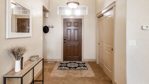 A hallway with a wooden door, a mirror, a console table with a vase, and a patterned rug. - TJ Rancher home, private yard, king beds, 2.5 bath (Twin Falls)