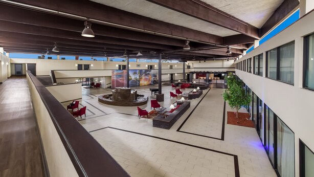 Eine großzügige Lobby mit einer zentralen Sitzecke, einer Wasserspiels und einem Wandgemälde.