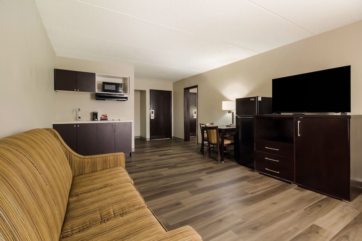 A compact living space with a sofa, kitchenette, dining area, and a TV.