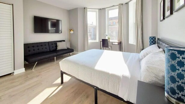 Ett modernt hotellrum med en stor säng, en soffa, en TV som är monterad på väggen och ett skrivbord med en stol.