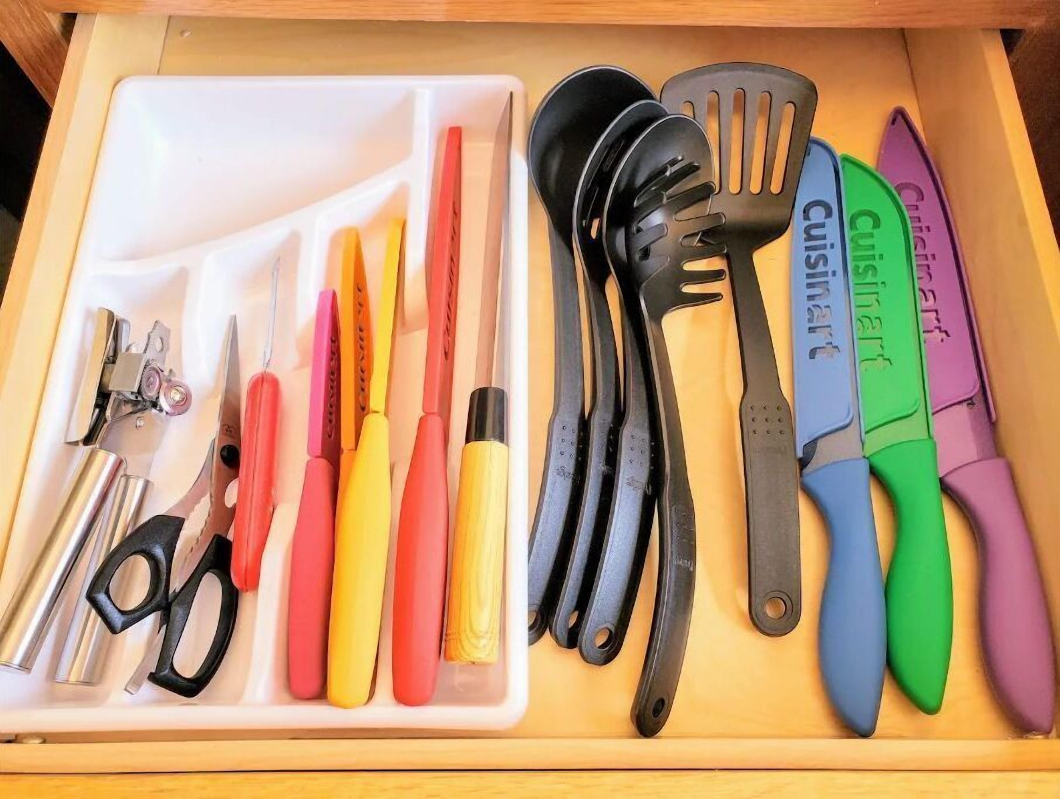 A drawer containing various kitchen utensils and tools, including scissors, spatulas, and a can opener.