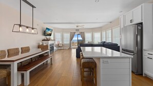 A modern kitchen with a central island, wooden benches, and a built-in refrigerator. - BEACHFRONT Home with HEATED POOL in North Cape May!!!! (North Cape May)