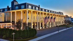 A hotel with a yellow facade, multiple stories, and a row of American flags. - BEACHFRONT Home with HEATED POOL in North Cape May!!!! (North Cape May)