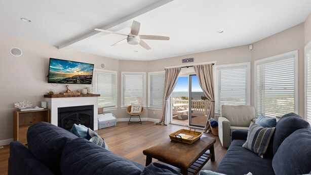 A spacious living room with a fireplace, comfortable seating, a television, and a balcony with a view. - BEACHFRONT Home with HEATED POOL in North Cape May!!!! (North Cape May)