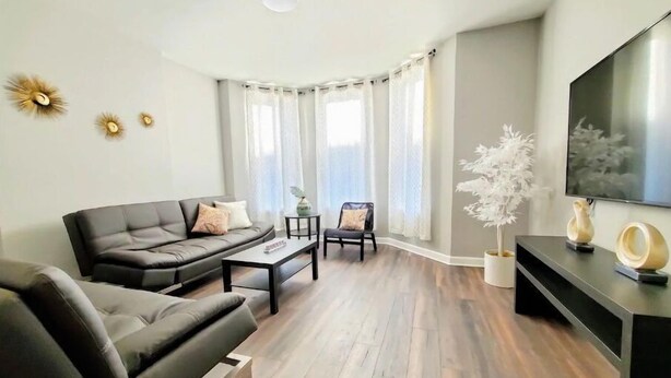 Un salon moderne avec un canapé gris, une table basse et un téléviseur posé sur un meuble noir.