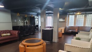 A modern lounge area with leather sofas, a central coffee table, and a bar area with stools. - Ansonia Hotel - Hostel (San Francisco)