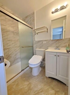 Une salle de bain avec une douche à parois de verre, des toilettes et un meuble-lavabo avec un miroir.