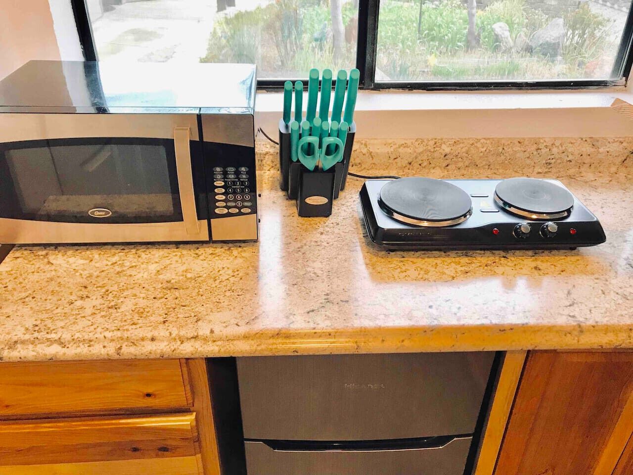 A kitchen with a microwave, toaster, and knife holder on a granite countertop.