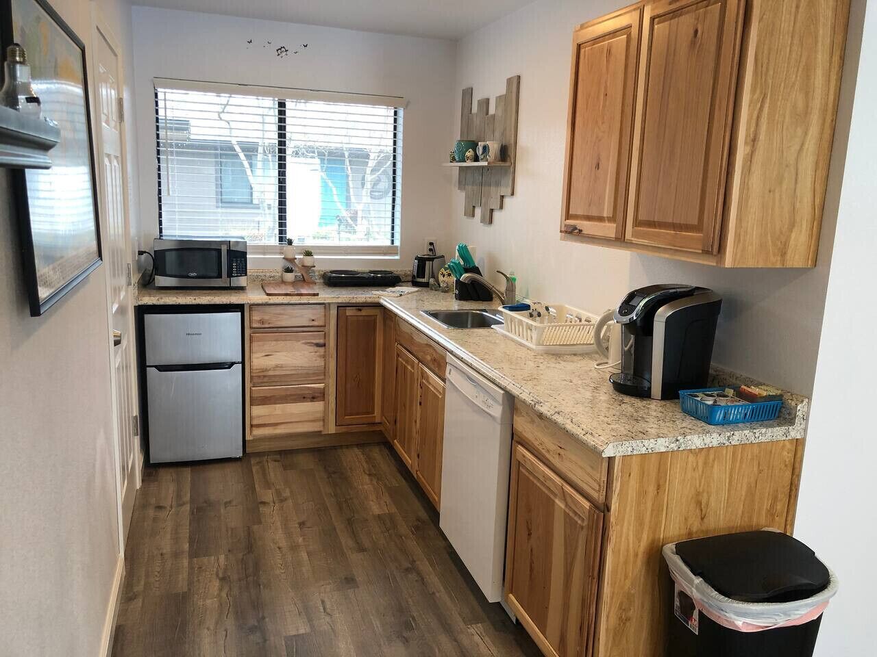 A compact kitchen with wooden cabinets, a built-in microwave, a refrigerator, and a dishwasher.