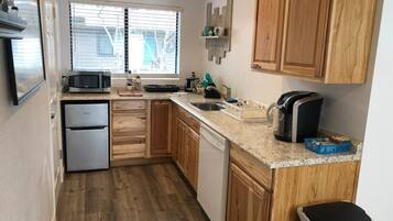 A compact kitchen with wooden cabinets, a built-in microwave, a refrigerator, and a dishwasher.