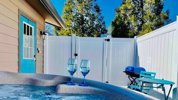 Ein Whirlpool mit zwei Wassergläsern, ein Grill und ein Tisch mit Stühlen im Hinterhof.