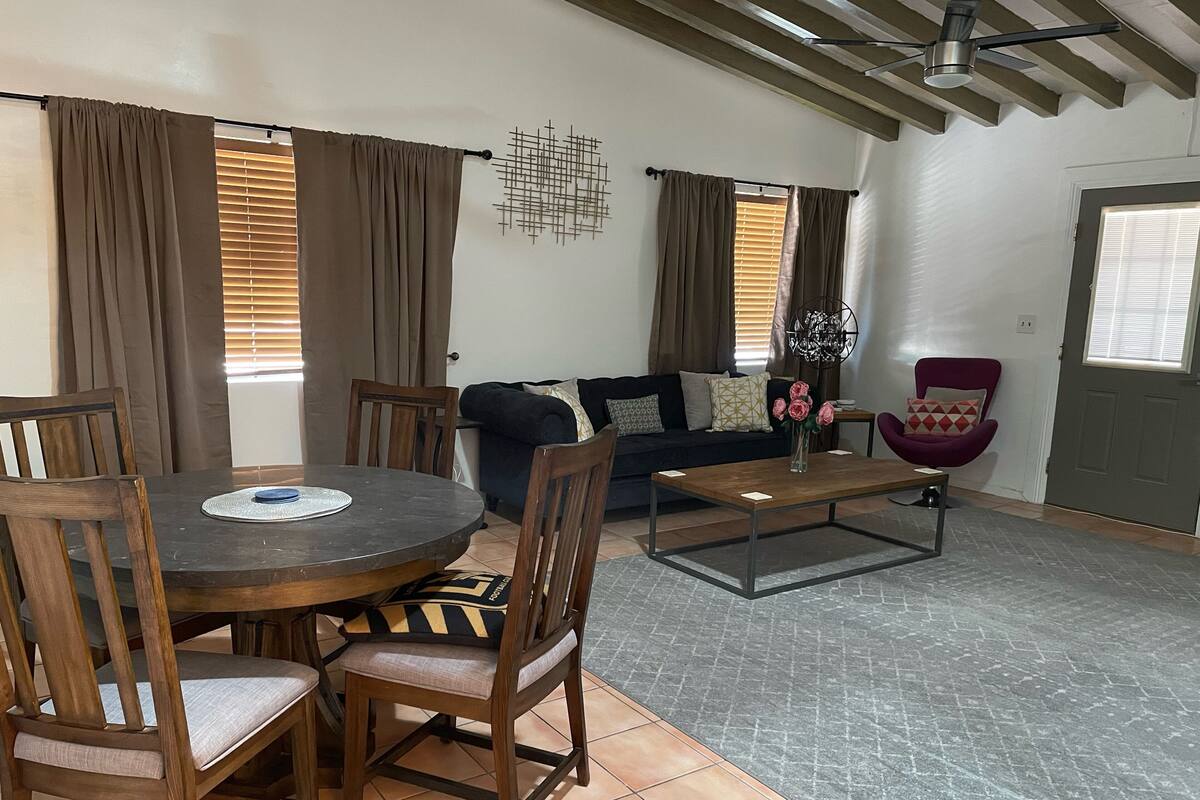 A living room with a round wooden table, four chairs, a sofa, and a coffee table.