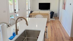 Une cuisine moderne dotée d’un îlot central, d’un évier en acier inoxydable et d’un revêtement de sol en bois.